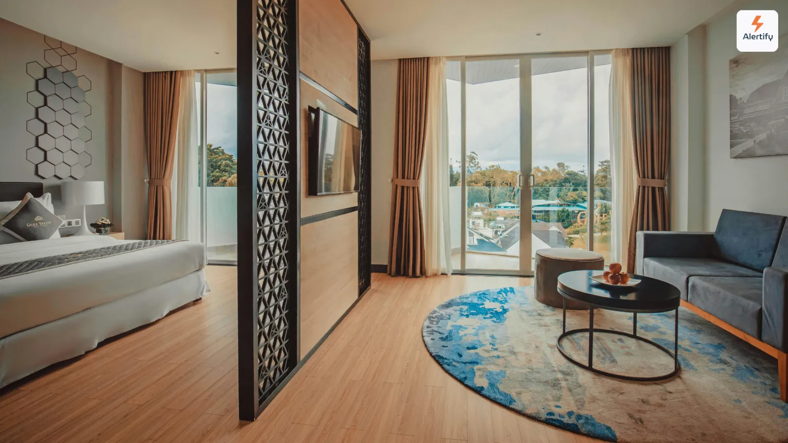 Suite moderna de alojamento local com cama feita, sofá azul e janelas de varanda do chão ao teto