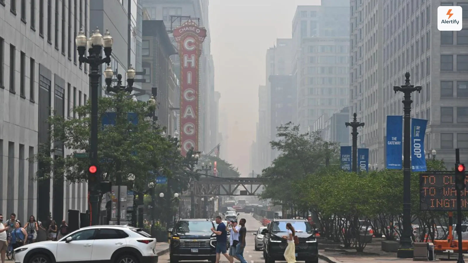 Neblina de fumo de incêndios florestais a engolir os edifícios de uma rua de Chicago, com o letreiro do Chicago Theatre iluminado em primeiro plano.