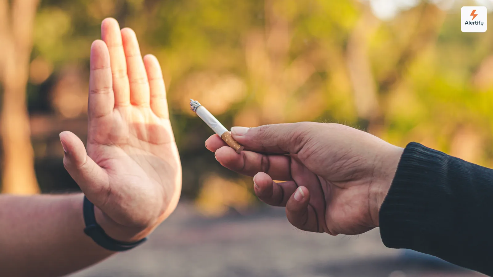 Mão levantada a recusar educadamente um cigarro aceso oferecido por outra pessoa no exterior