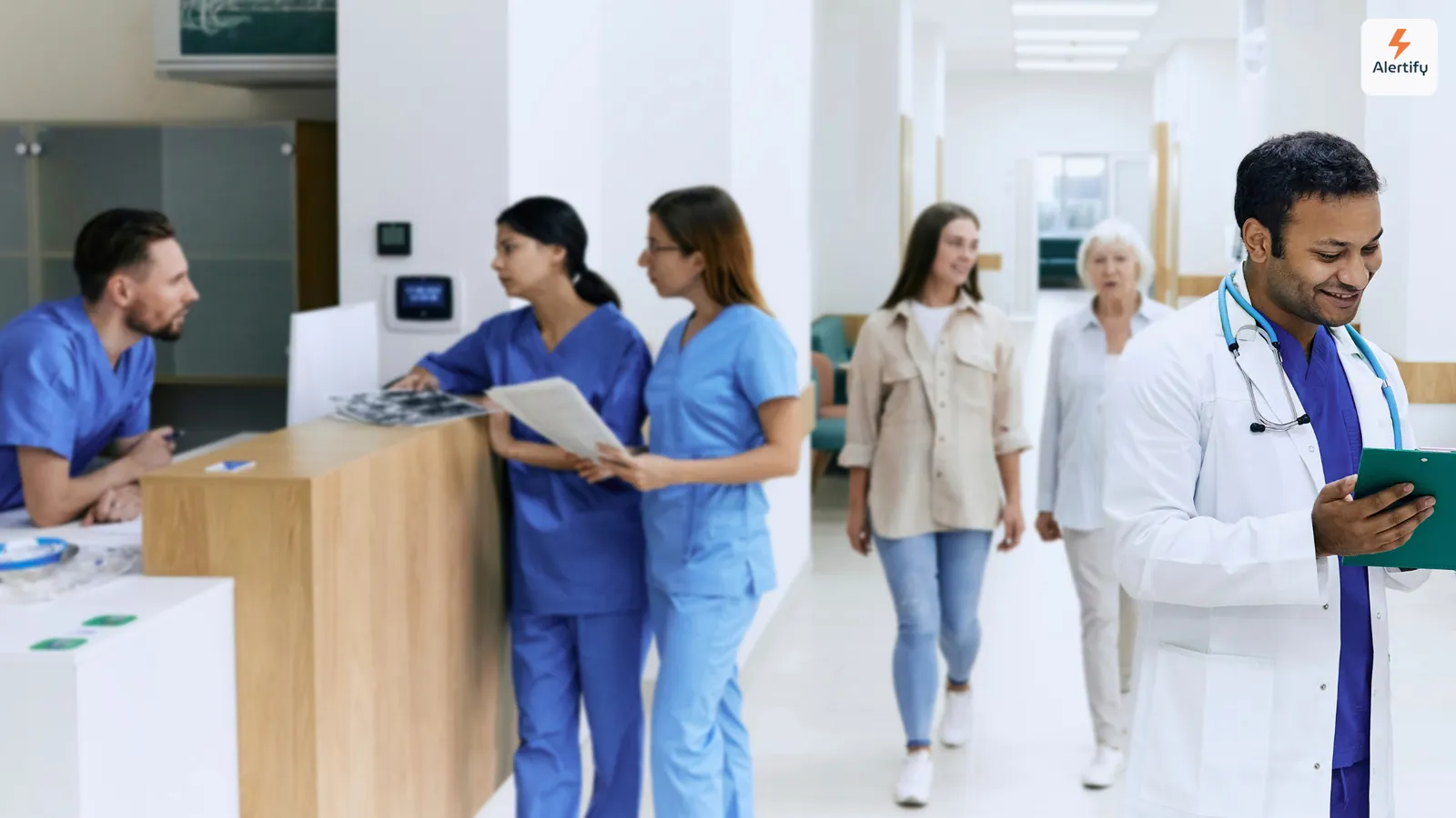Clínicos e visitantes a passar junto ao balcão de receção no átrio luminoso de um hospital